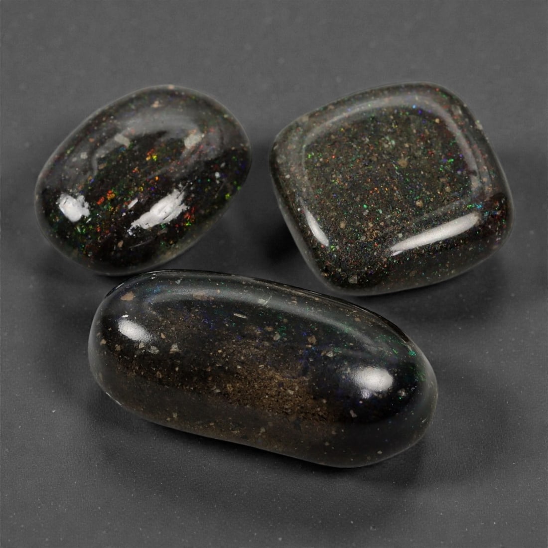 73.40 Carats Dark Matrix Opal Trio - Natural Australian Stones, 20-32mm, 18XK: This intriguing trio of matrix opals reveals a deep, earthy palette interspersed with vibrant flashes of red, green, and violet fire. Encased in a naturally dark host rock, the play-of-color emerges i