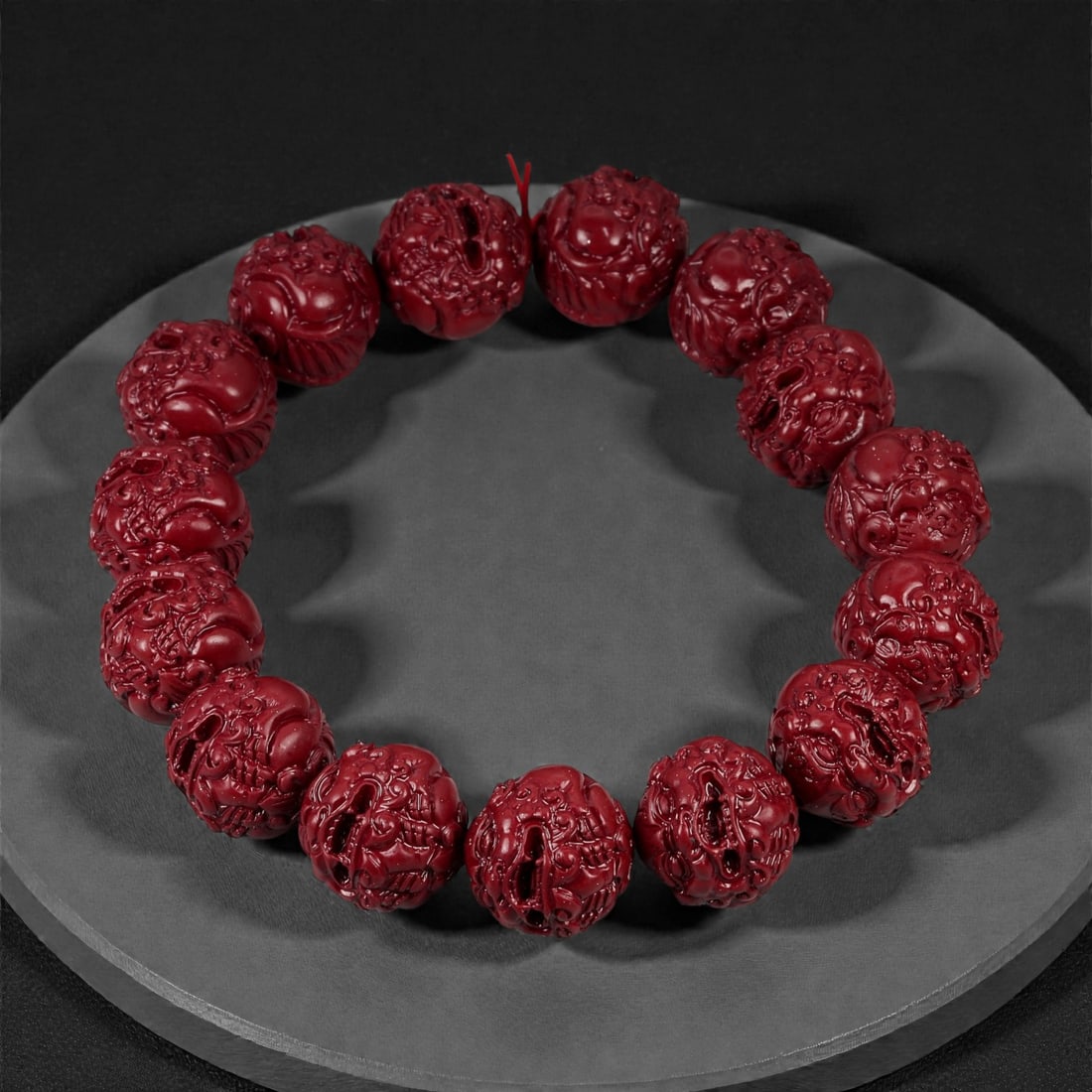 A Chinese Cinnabar Carved Bead Bracelet, 20th Century, 42FD: Composed of spherical beads carved from cinnabar, a mercury sulfide material traditionally employed in Chinese ornamental and ritual objects. Each bead is pierced centrally and carved in openwork and