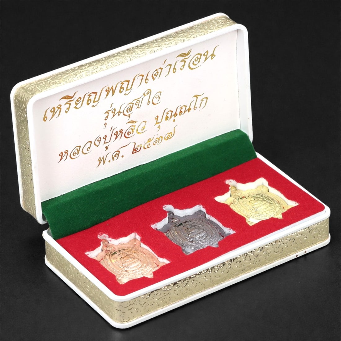 A Thai Bronze Tortoise-Form Amulet Set, Late 20th Century, 27FJ: The set comprises three tortoise-shaped amulets cast in bronze with differing surface finishes, including copper-toned, dark patinated, and gilt examples. Each amulet is modeled in low relief with a d