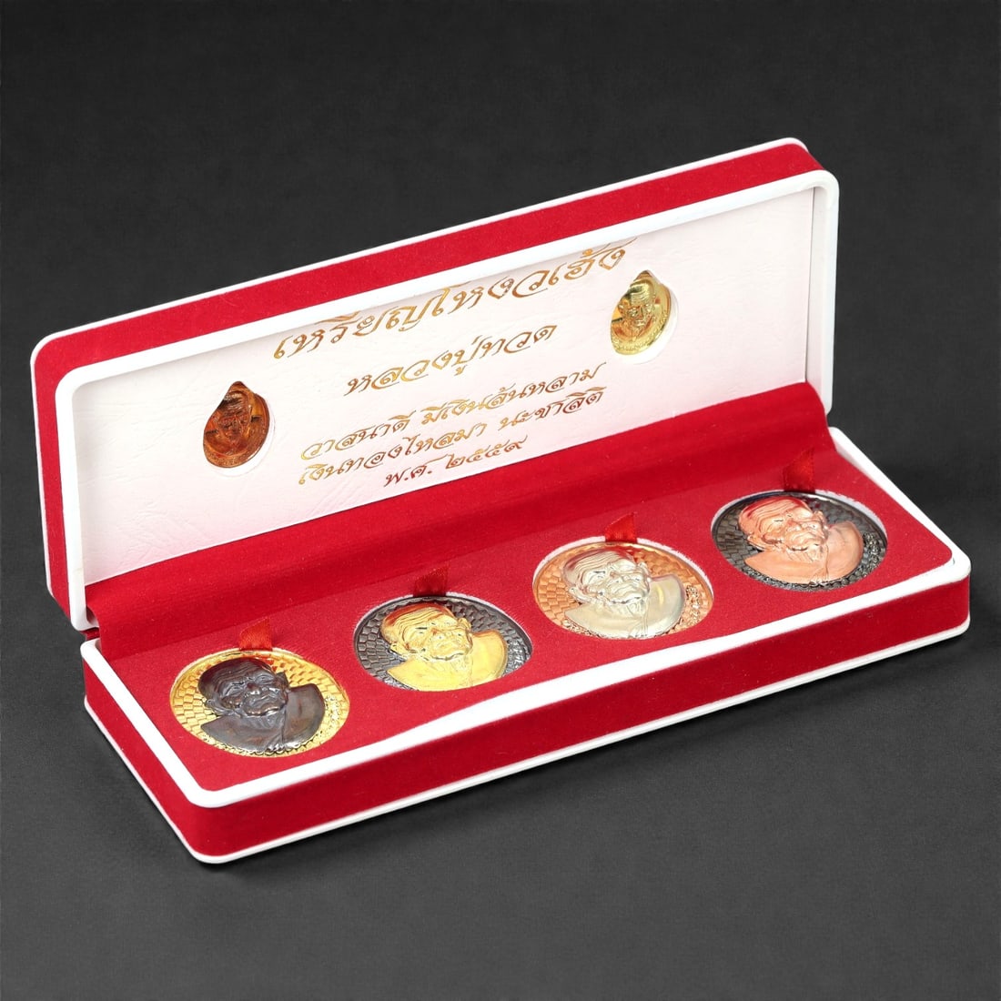 A Thai Gilt and Bronze Monk Medallion Set, Late 20th-Early 21st Century, 50FJ: The set comprises four circular portrait medallions cast in bronze with gilt and mixed-metal finishes, each depicting a Buddhist monk in high-relief bust form. The monk is rendered with individualized