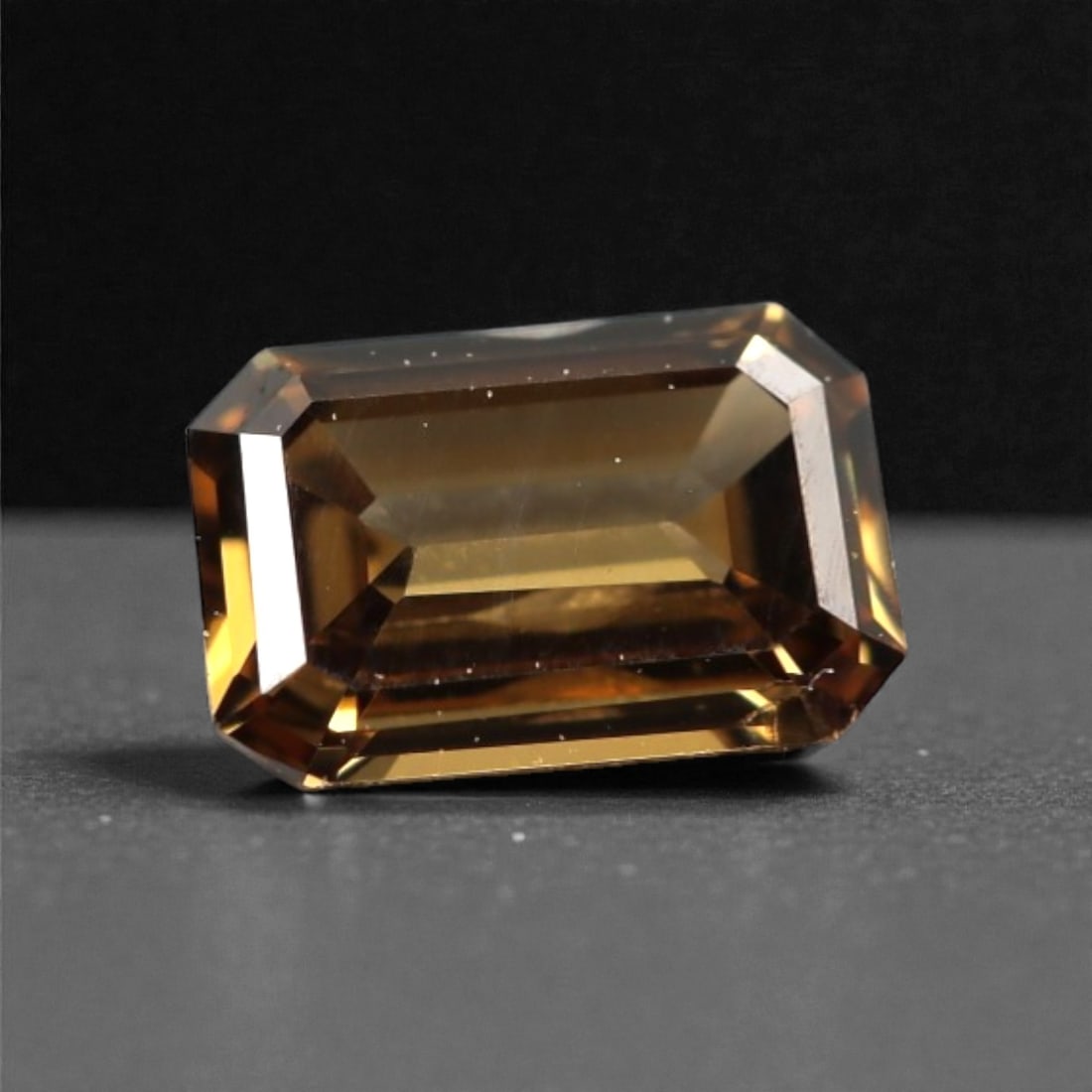 0.19 Carats Fancy Deep Brownish Yellow Diamond - Natural South African Origin, 13DA: This 0.19 carat fancy deep brownish yellow diamond captivates with a rich, earthy hue that evokes the warmth of aged amber and the depth of fine cognac. The emerald cut enhances the stone's natural al
