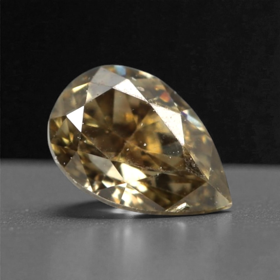 0.23 Carats Fancy Light Brownish Yellow Diamond - Natural South African Origin, 7DA: This 0.23 carat fancy light brownish yellow diamond glows with a soft, champagne hue, its pear brilliant cut amplifying a luminous, lively sparkle across every precisely polished facet. The warm, pale