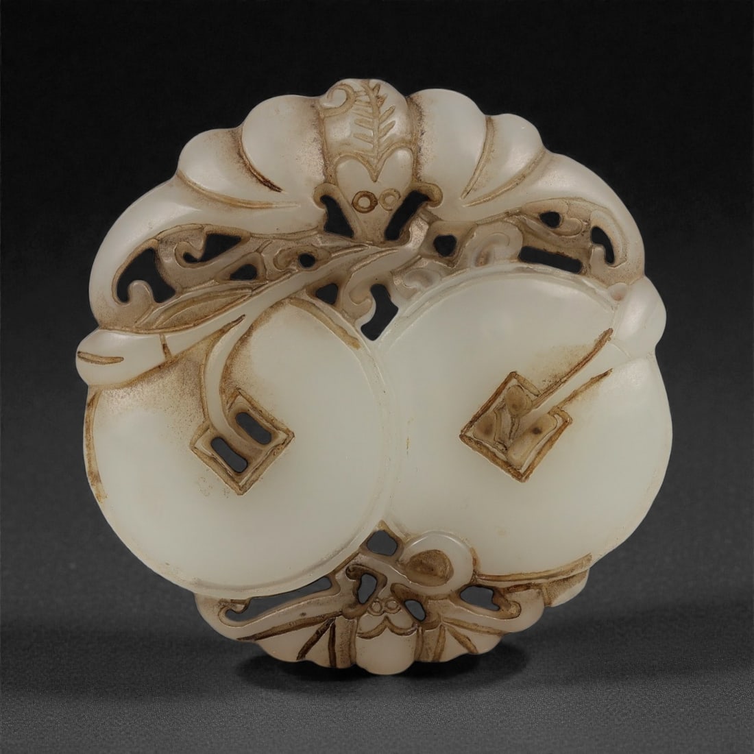 A Chinese Hetian Jade Plaque with Bats and Coins, 20th Century, 96FD: Carved from creamy white Hetian jade with light translucency, the plaque is worked in openwork relief and polished overall. The circular form is decorated with stylized bats arranged around paired coi