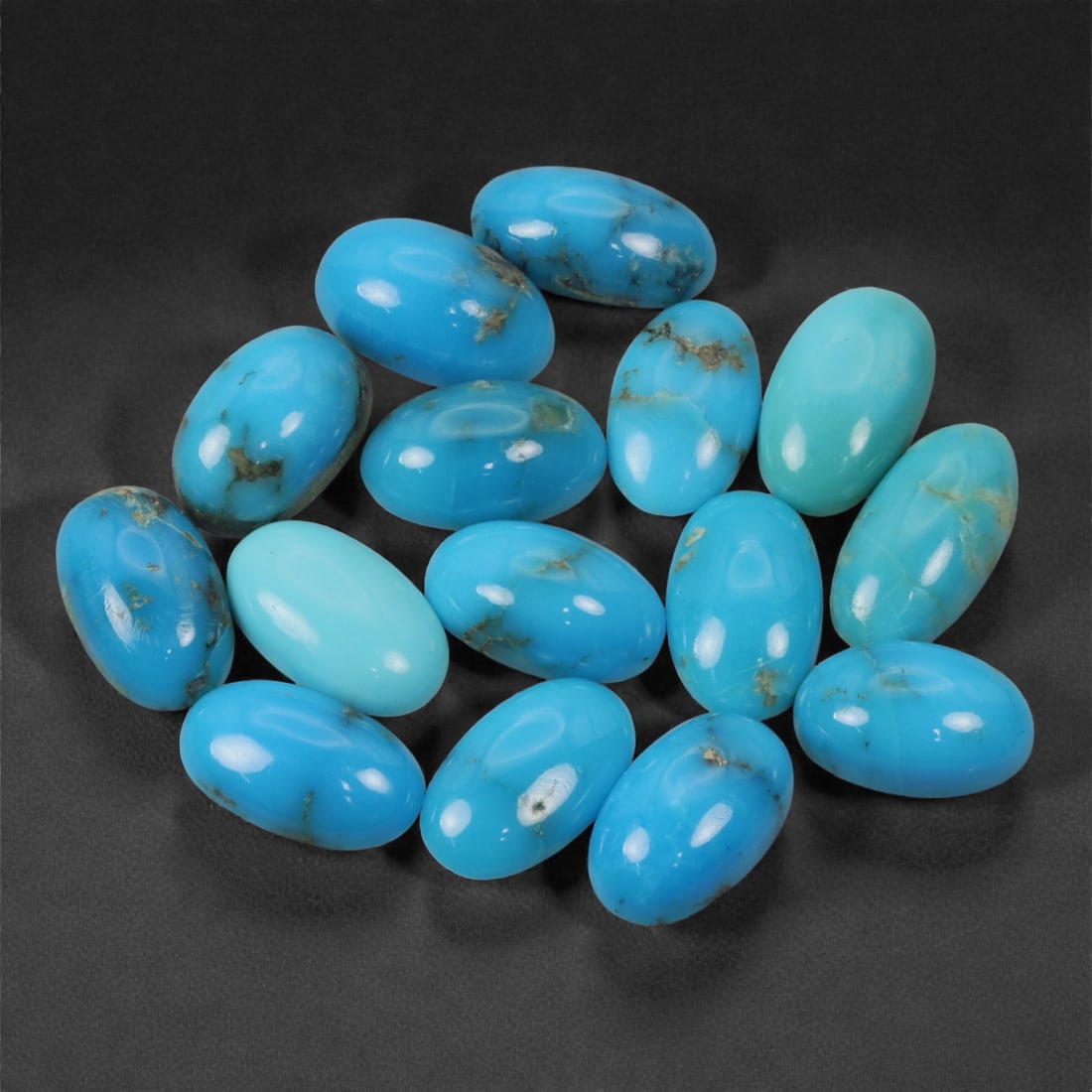 19.44 Carats Sky Blue Turquoise Cabochon Lot - Natural Persian-Origin Style, 38XJ: This vivid lot of oval turquoise cabochons showcases a striking range of bright sky blues and robin's egg tones, with delicate matrix patterns adding natural character to select stones. The high polis