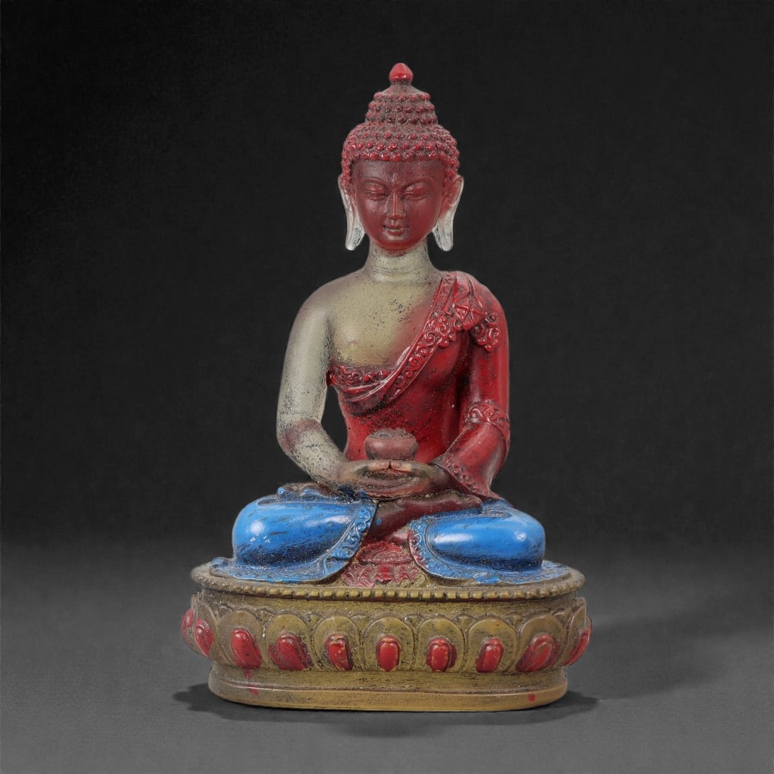 A Chinese Glass Figure of the Buddha, 20th Century, 49FG: Modeled from molded glass with polychrome surface decoration, the figure represents the Buddha seated in dhyana posture on a circular lotus pedestal. The hands are held in meditation gesture, supporti