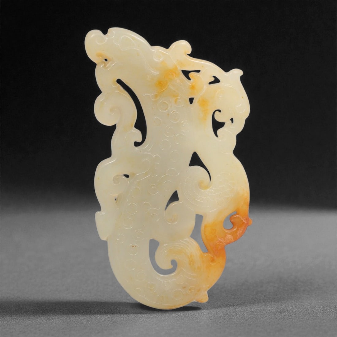 A Chinese Archaistic Jade Openwork Plaque with Dragon and Phoenix, 20th Century, 36YC: The plaque is carved from pale celadon jade with areas of warm russet and honey-colored inclusions, the stone exhibiting soft translucency and a finely polished surface. It is worked in openwork relie