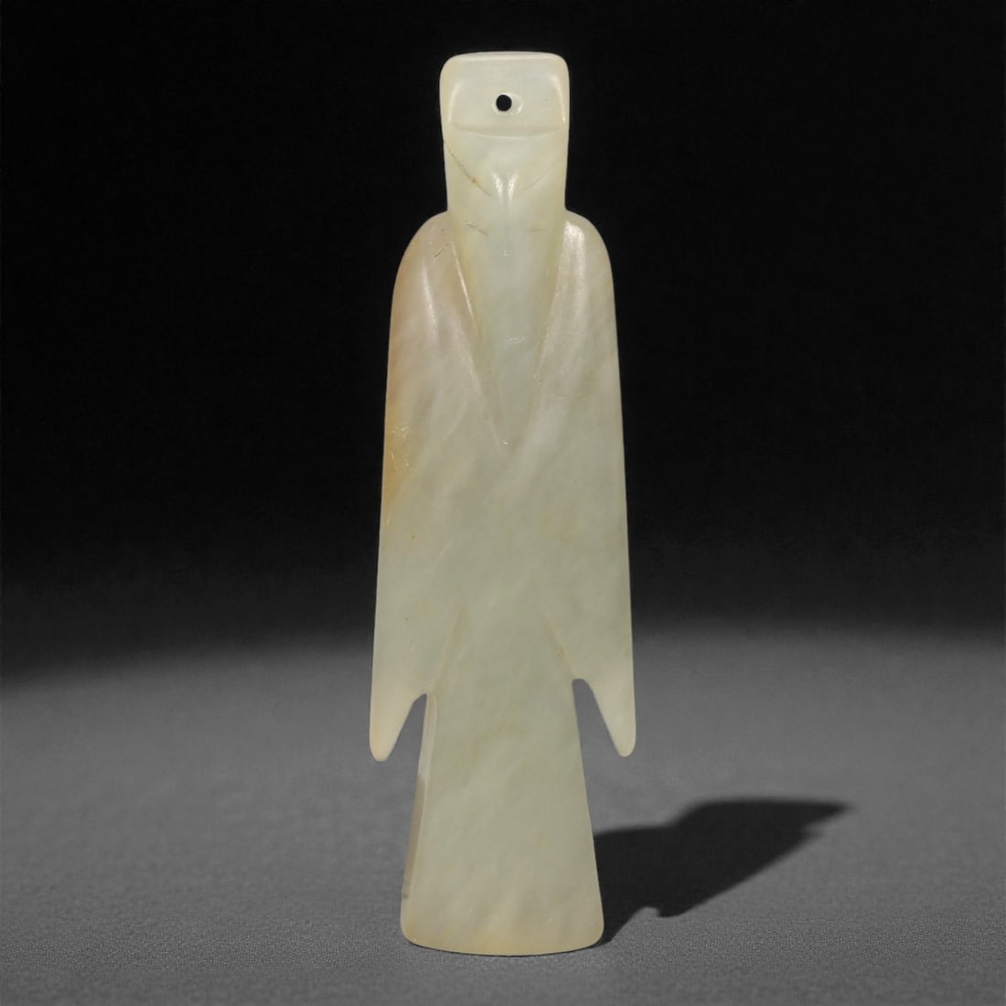 A Chinese Hetian Jade Idol Figure, 20th Century, 81FH: Carved from pale celadon Hetian nephrite jade with faint cloudy translucency and minor natural inclusions, the figure is worked as a slender standing form with a flattened body and simplified silhouet