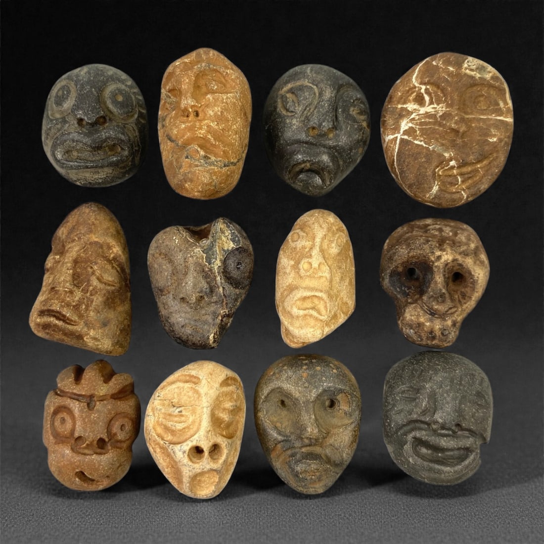 A Lot of Ancient Mediterranean Stone Maskettes, 12th-17th Century, 2.5-3.2cm, 42V: The group comprises lot of small maskettes carved from various stone types, including limestone and related sedimentary materials, displaying a range of natural tones from pale beige and ochre to dark
