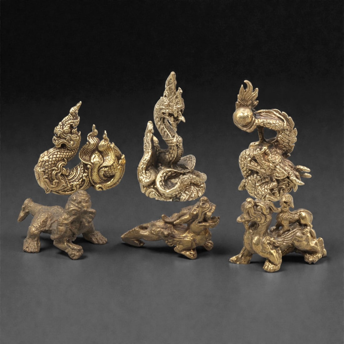A Group of Thai Copper Alloy Mythological Animal Figures, 20th Century, 5ZG: Cast in copper alloy with a warm gilt surface and areas of darker patination, the group comprises a selection of small-scale mythological animal figures drawn from Thai decorative and religious tradit