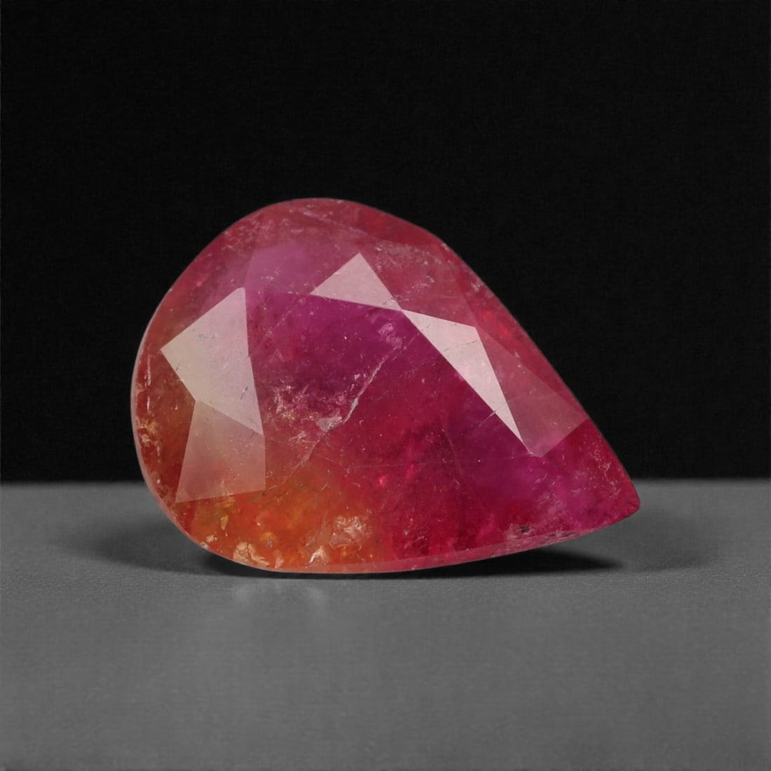 6.10 Carats Sunset Pink-Orange Tourmaline Gem - Natural Mozambique Stone, 15.1x11.2x5.6mm, 10XK: This vivid tourmaline radiates with a fiery blend of saturated magenta, deep pink, and sunset orange tones, creating a dynamic gradient that shifts with the light. Its custom pear-like cut accentuates