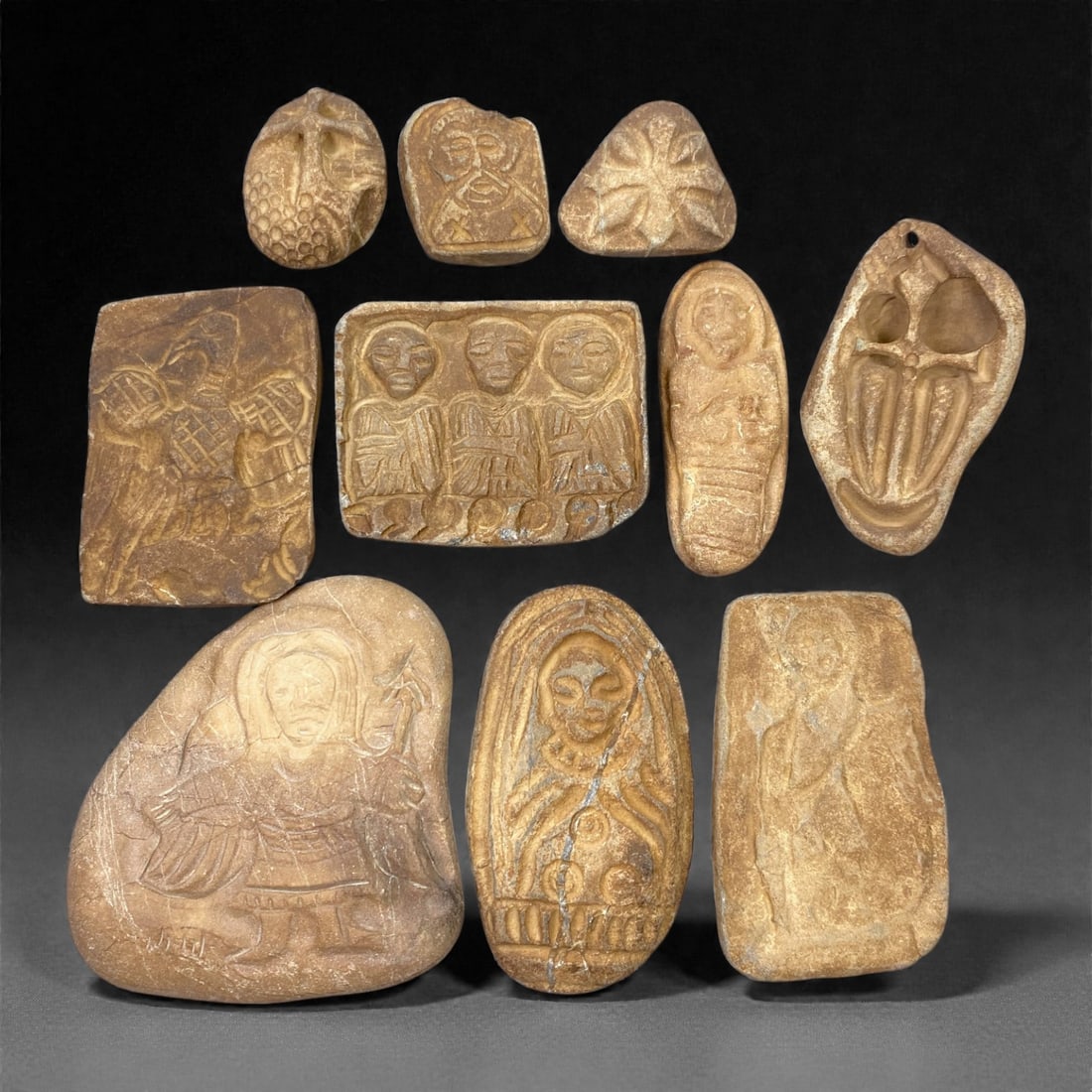 A Group of Medieval Christian Stone Devotional Objects, 12th-15th Century, 96W: Carved from light beige to warm brown stone with visible veining, inclusions, and areas of surface wear, the group comprises ten small devotional plaques and reliefs executed in low relief. The assemb