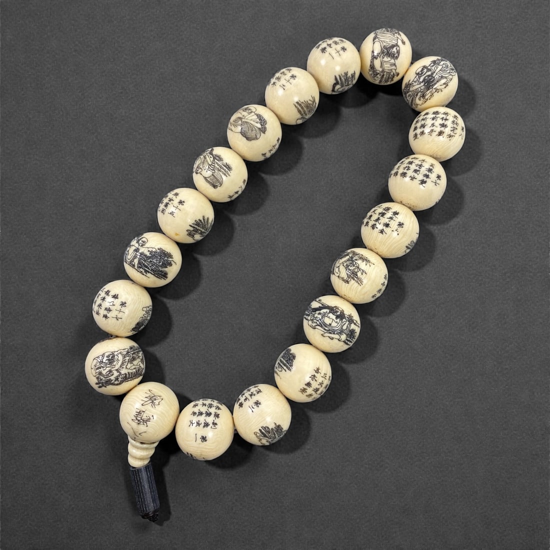 An Engraved Beaded Necklace, 20th Century, 35FJ: The necklace is composed of a strand of spherical beads carved from an unidentified pale organic material, visually reminiscent of ivory but here described without attribution, each bead finely engrav
