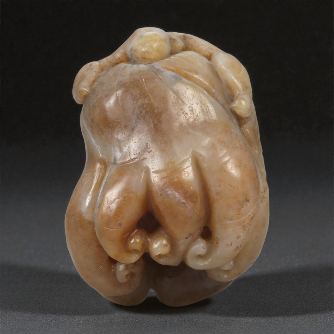 A Chinese Jade Ginseng-Form Pendant, 20th Century, 32YA: Carved from pale brown jade with areas of creamy translucency and natural surface mottling, the pendant is worked in the round in the form of a ginseng root. The main body is modeled as a bulbous cent
