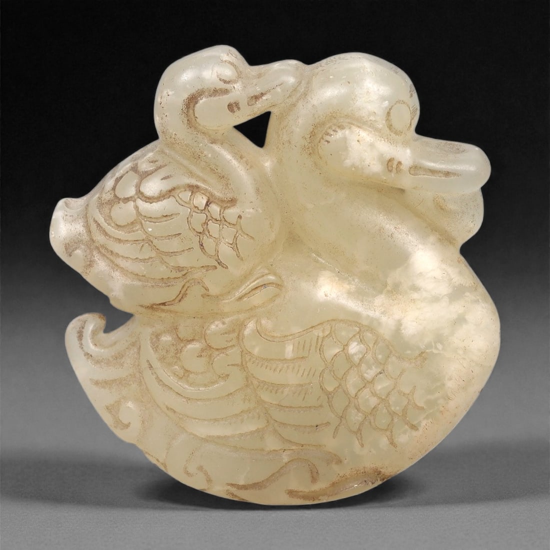 A Chinese Hetian Jade Zoomorphic Plaque, 20th Century, 50FH: Carved from pale creamy-white Hetian jade with areas of light russet staining and natural inclusions, the plaque is formed as a compact zoomorphic creature rendered in low relief with softly rounded c