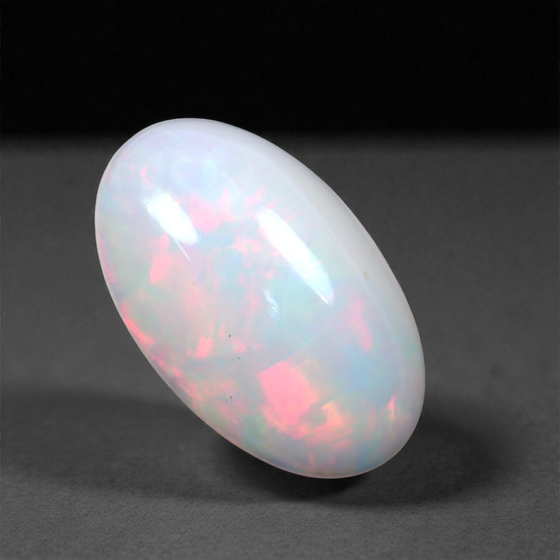 4.01 Carats Oval Cabochon Opal - Natural Ethiopian Stone 16x9.8x5.5mm, 17XH: Glowing with soft romance, this oval Welo opal exhibits a radiant play-of-color in swirling tones of rose pink, coral, and icy lavender. The gem's translucent body allows its fire to shimmer from with