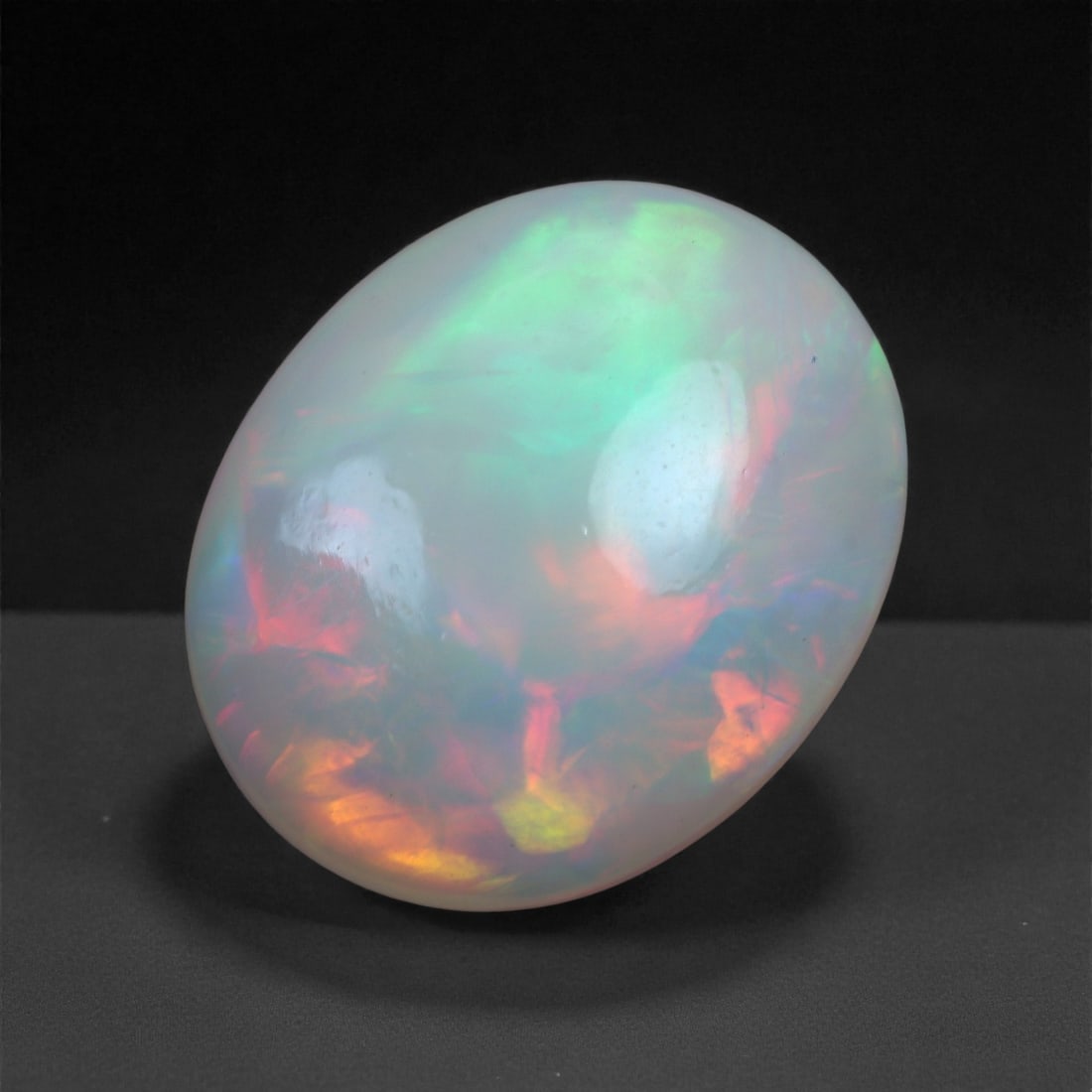 3.52 Carats Play-of-Color Welo Opal - Natural Ethiopian Gem 13x10mm, 37XA: This captivating Welo opal gleams with a luminous cascade of multi neon color that ripple across the stone's surface with every movement. The play-of-color is vivid and well-distributed, presenting a