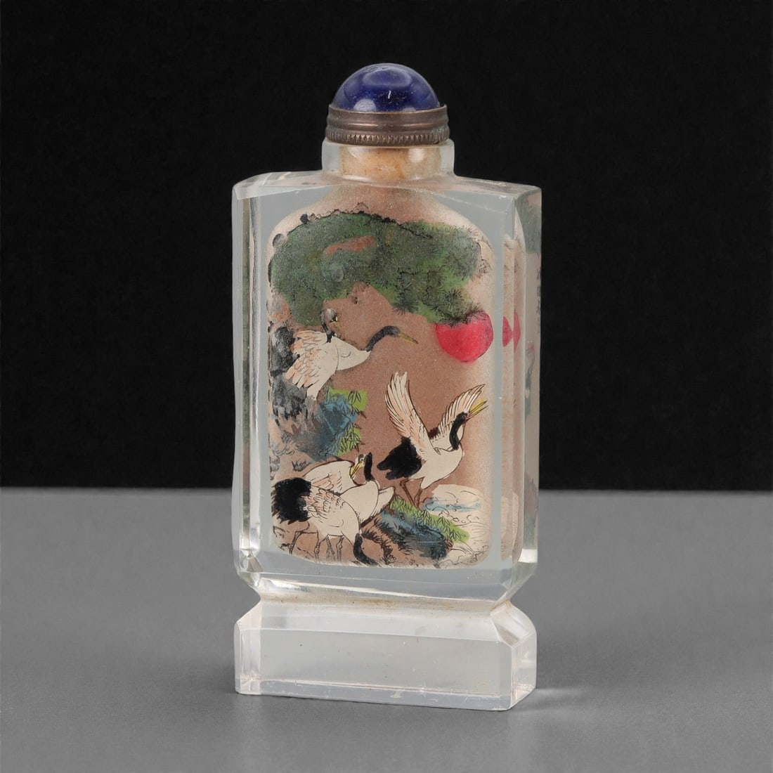 A Chinese Crystal Glass Inside-Painted Snuff Bottle, 20th Century, 62FG: The snuff bottle is formed from clear crystal glass and of flattened rectangular section, raised on a stepped rectangular foot and rising to a short cylindrical neck with a flat rim. The interior is p