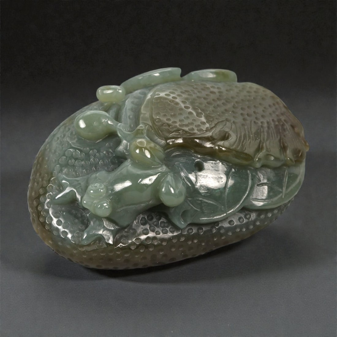 A Chinese Nephrite Jade Frog on Lotus, 20th Century, 74FB: Carved from pale green nephrite jade with areas of darker mottling and natural translucency, the object is worked in the form of a crouching frog resting upon a lotus leaf. The frog is rendered in low