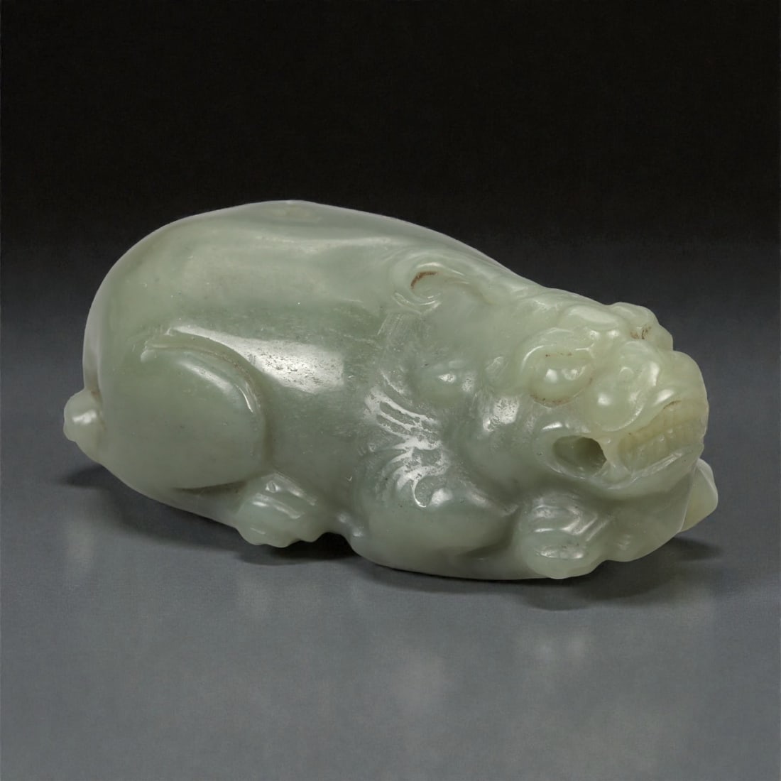A Chinese Nephrite Jade Pixiu Figure, 20th Century, 73YA: Carved from pale celadon-green nephrite jade with areas of soft translucency and minor natural inclusions, the figure represents pixiu, the mythical beast traditionally associated with protection and