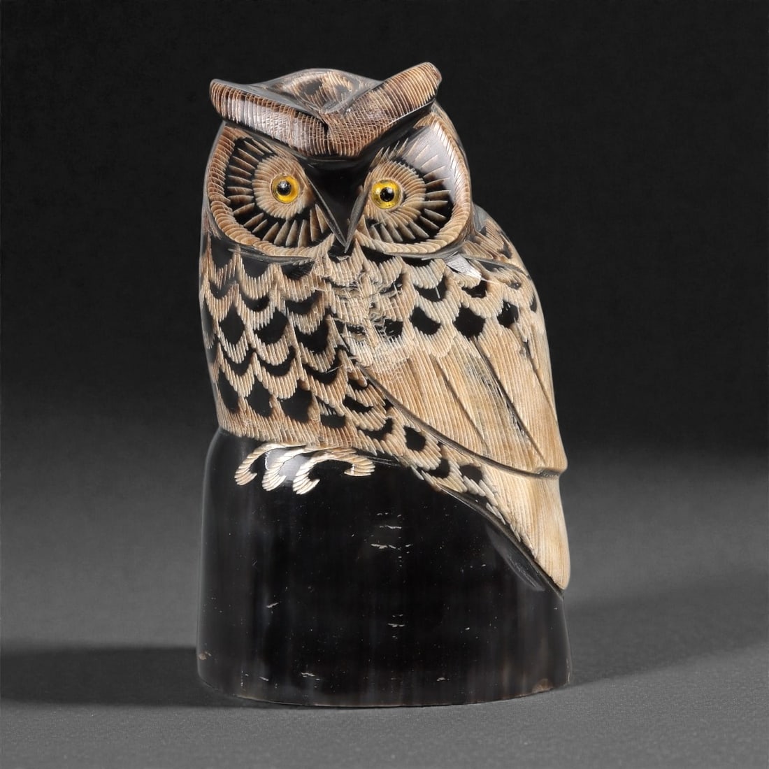 An East Asian Ox Horn Owl Effigy, 20th Century, 9FJ: Carved from a single section of ox horn with pronounced natural striations and tonal variation from pale beige to deep brown, the effigy is modeled as a standing owl rendered in the round. The head is