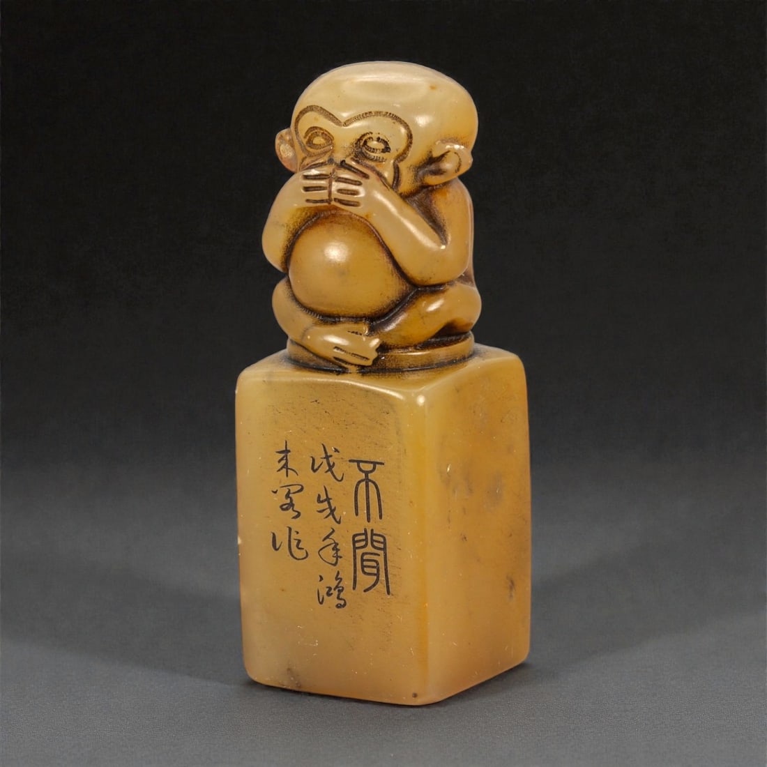 A Chinese Stone Seal with Monkey Finial, 20th Century, 16FA: Carved from a honey-toned stone with subtle natural inclusions and scattered darker specks, the seal is surmounted by a sculptural monkey finial carved in the round. The monkey is shown seated, with o