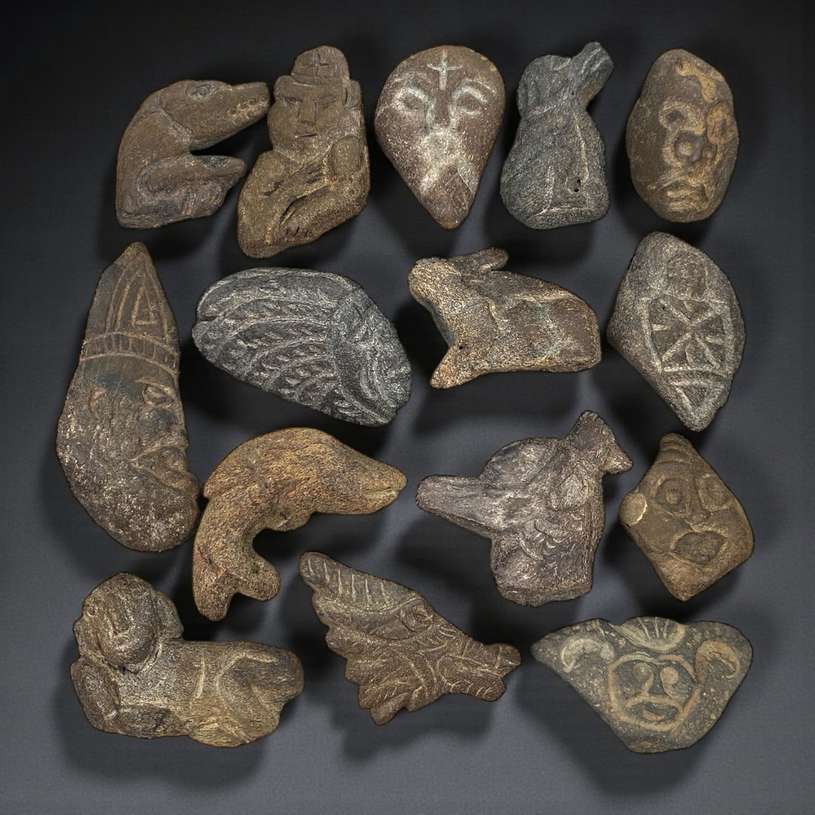 A Near Eastern Bone Amulet Group, 3rd-1st Millennium BCE, 72W: The group comprises fifteen small amulets carved from bone, worked predominantly in low relief and presenting a varied corpus of schematic zoomorphic and anthropomorphic forms; the material displays n
