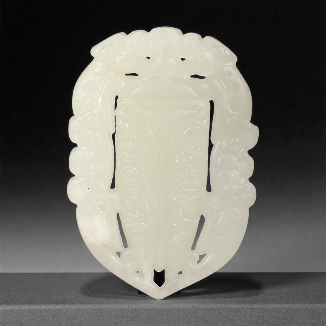 A Chinese Archaistic-Style Jade Openwork Plaque, 20th Century, 43FH: Carved from pale translucent jade with a milky white tone and subtle internal clouding, the plaque is formed as a vertically oriented openwork panel with a symmetrical outline tapering to a pointed lo