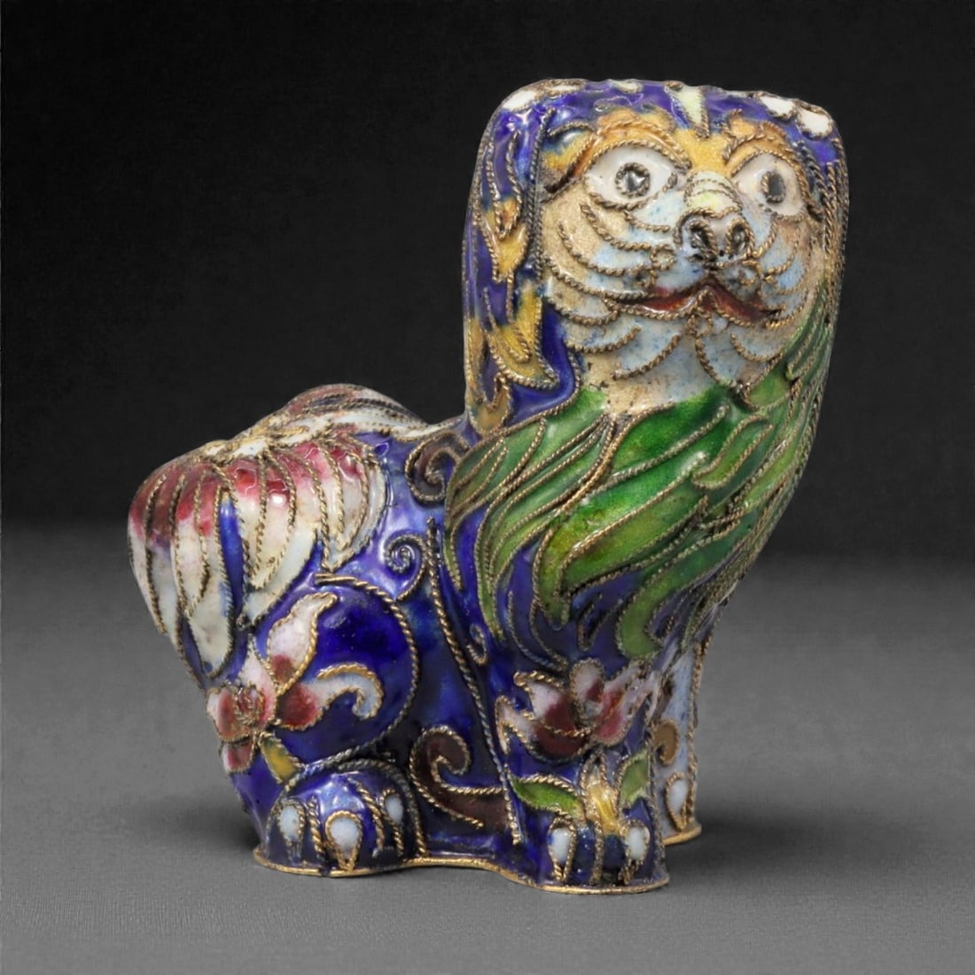 A Chinese Cloisonne Enamel Lion Effigy, 20th Century, 72YC: Constructed in copper and decorated with polychrome cloisonne enamel, the figure represents a stylized lion shown seated with the head turned slightly upward in an alert, expressive pose. The face is