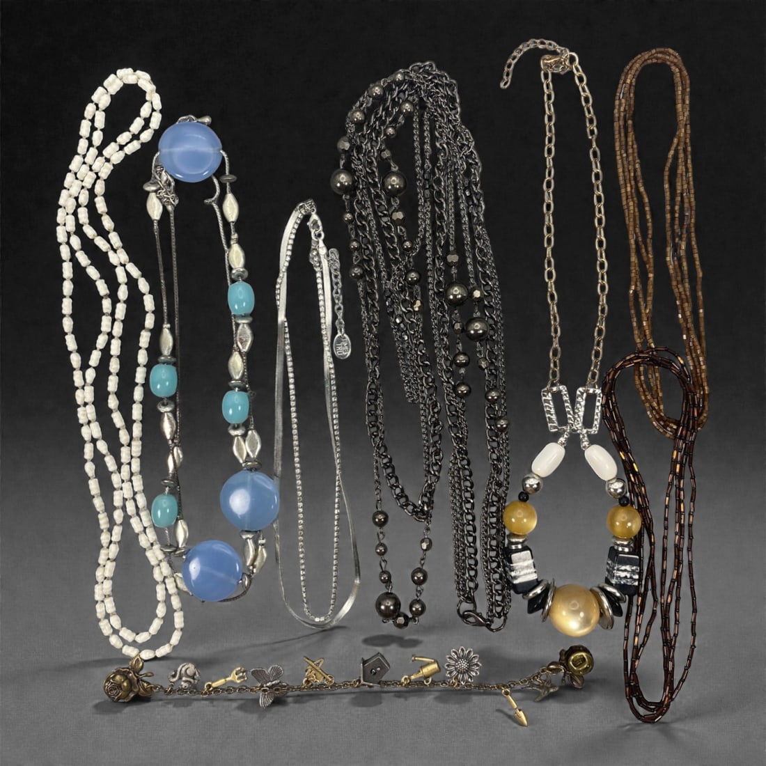 An Estate Lot of Eight Necklaces, Late 20th Century, 70FK: The lot comprises eight necklaces, crafted from glass, semi-precious stone, metal, and resin, with varied chain and beaded constructions. The pieces include: a multi-strand necklace of small white gla