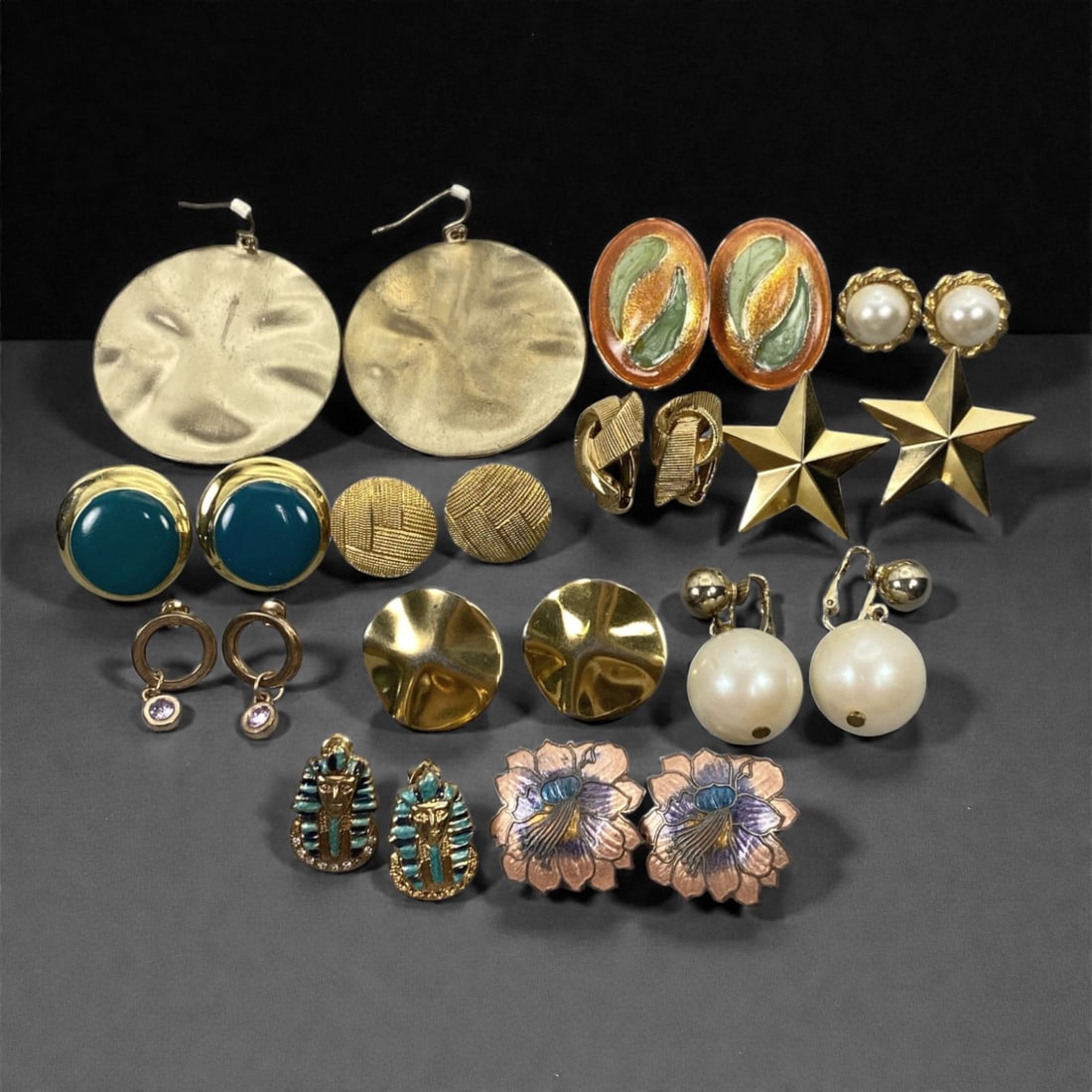 An Estate Lot of Twelve Pairs of Earrings, Late 20th Century, 86FK: The lot comprises twelve pairs of earrings, crafted from gilt and silver-toned alloy, with enamel, faux pearl, glass, and crystal accents. The pieces include: large disc-shaped gilt drop earrings with