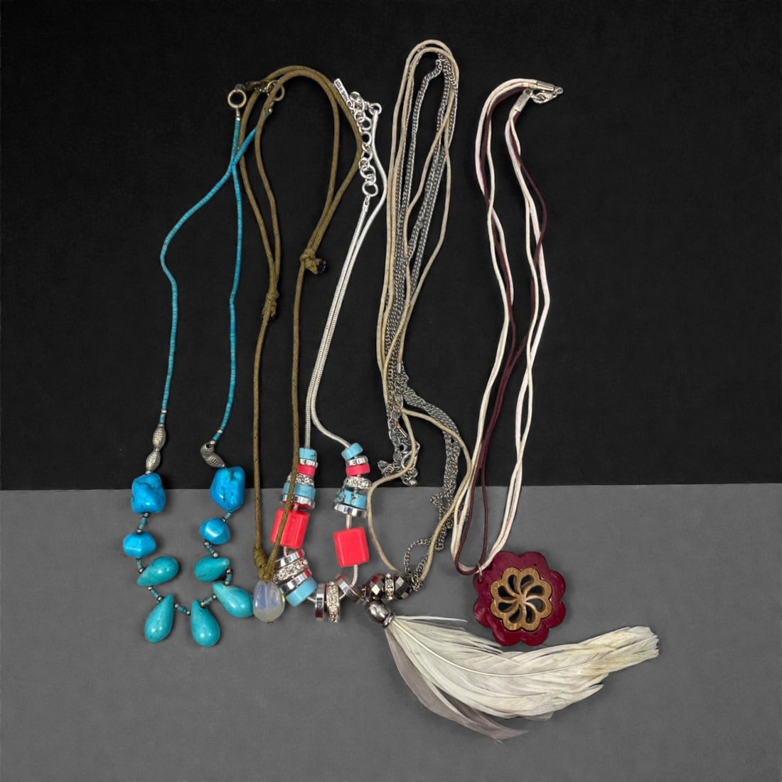 An Estate Lot of Five Necklaces, Late 20th Century, 65FK: The lot comprises five necklaces constructed from mixed materials, including cord, metal chain, stone, glass, and organic elements. One piece features a double-strand design with polished turquoise-co