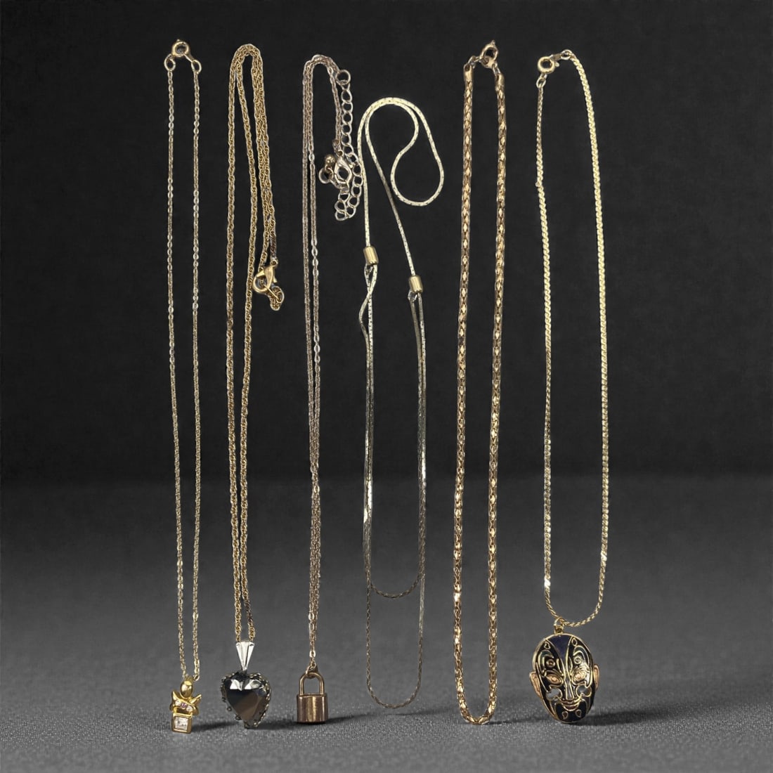 An Estate Lot of Six Necklaces, Late 20th Century, 80FK: The lot comprises six necklaces, crafted from gilt and silver-toned alloy, with crystal, enamel, and glass accents. The pieces include: a fine gilt cable chain with a small, articulated cat pendant se