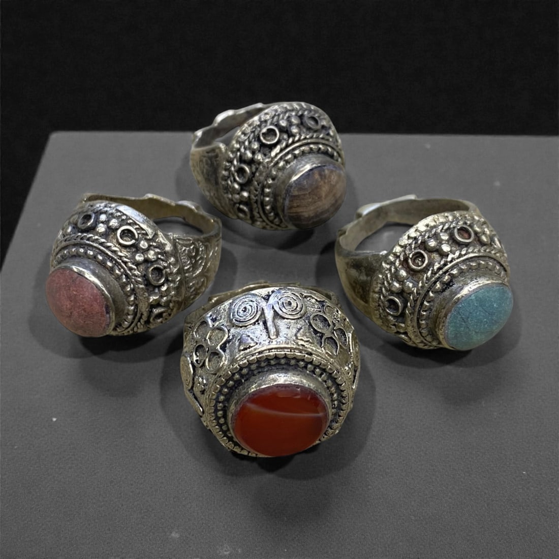 A Group of Four Antique Silvered Bronze Rings, 19th Century, Size 7.5-8US, 64g, 61AA: Each ring is crafted from silvered bronze, featuring ornate metalwork including filigree, repousse, and granulation details. The bezels are set with composite stones, the surfaces exhibit minor patina