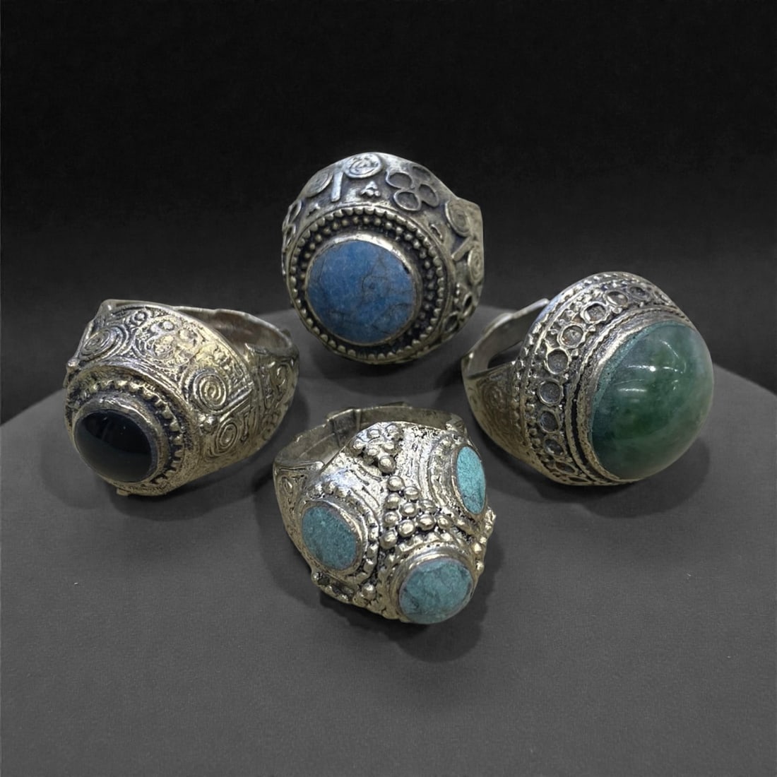 A Group of Four Antique Silvered Bronze Rings, 19th Century, Size 8US, 61g, 69AA: Each ring is crafted from silvered bronze, featuring ornate metalwork including filigree, repousse, and granulation details. The bezels are set with composite stones, the surfaces exhibit minor patina