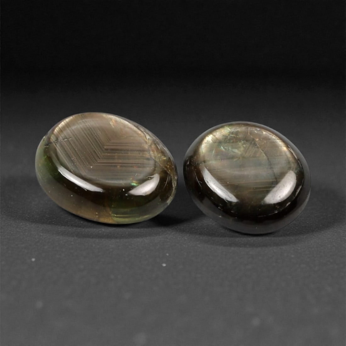 4.45 Carats Star Sapphire Cabochon Selection - Natural Burmese Stones, 344A: This curated selection of two oval cabochon-cut star sapphires from Burma exhibits a deep, velvety greenish-brown hue, reminiscent of twilight over a forested landscape. Each stone is precision-cut to