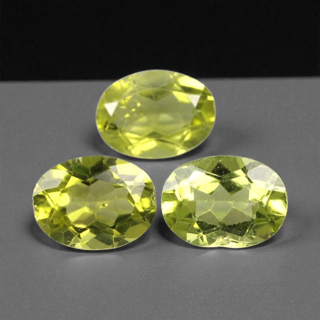 3.95 Carats Bright Green Peridot Selection - Natural Pakistani Stones, 368A: This curated selection of three oval-cut peridot gems radiates with a vibrant, lime-green hue, evoking the lush vibrancy of sunlit tropical foliage. Each stone is precision-faceted to maximize light d