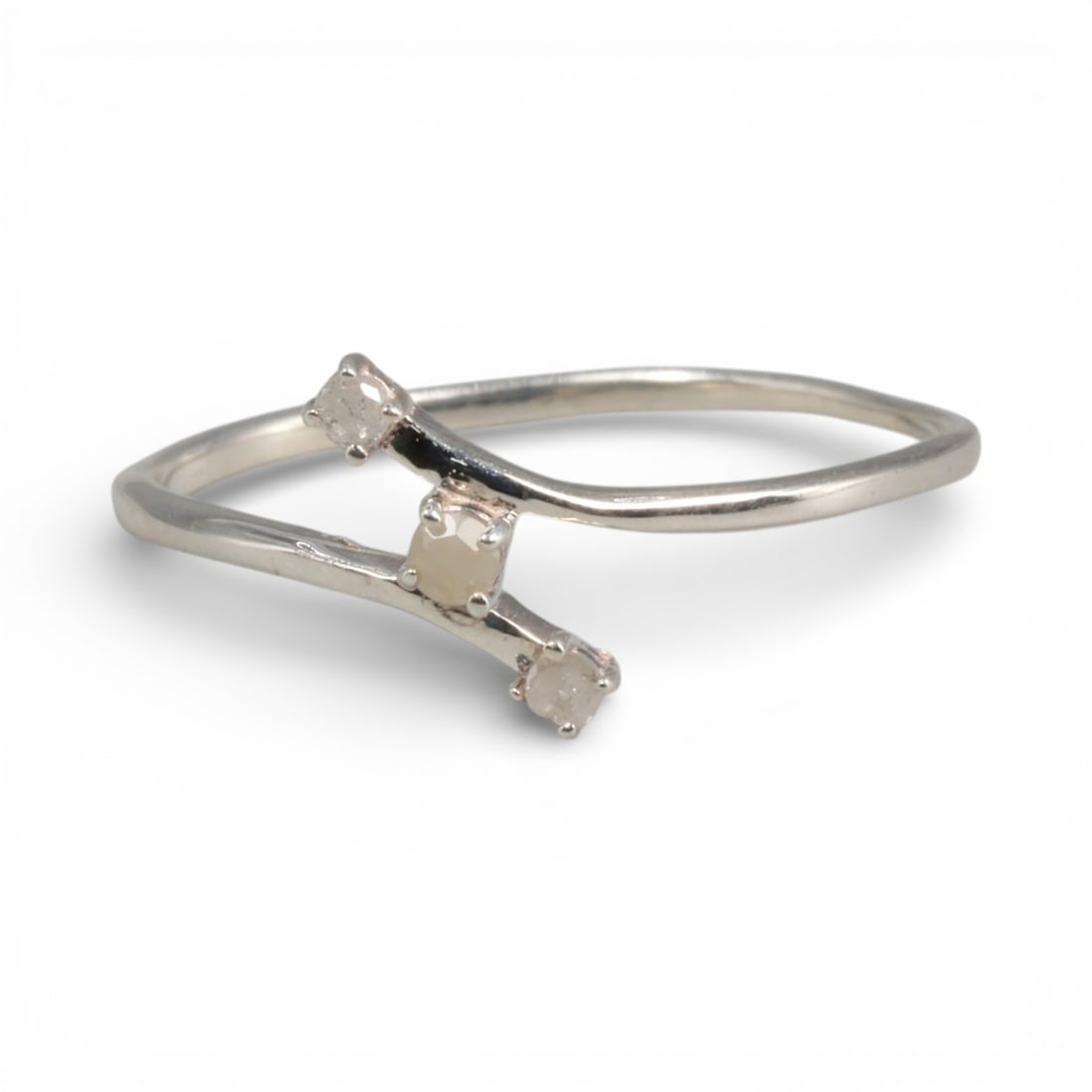 Sterling Silver (925) Ring with Three Diamonds - Size 7 US, 128A: This modern ring is crafted from polished sterling silver, featuring a distinctive bypass (crossover) design. The two fluid, curved shanks converge to hold three small, round-cut diamonds: a central c