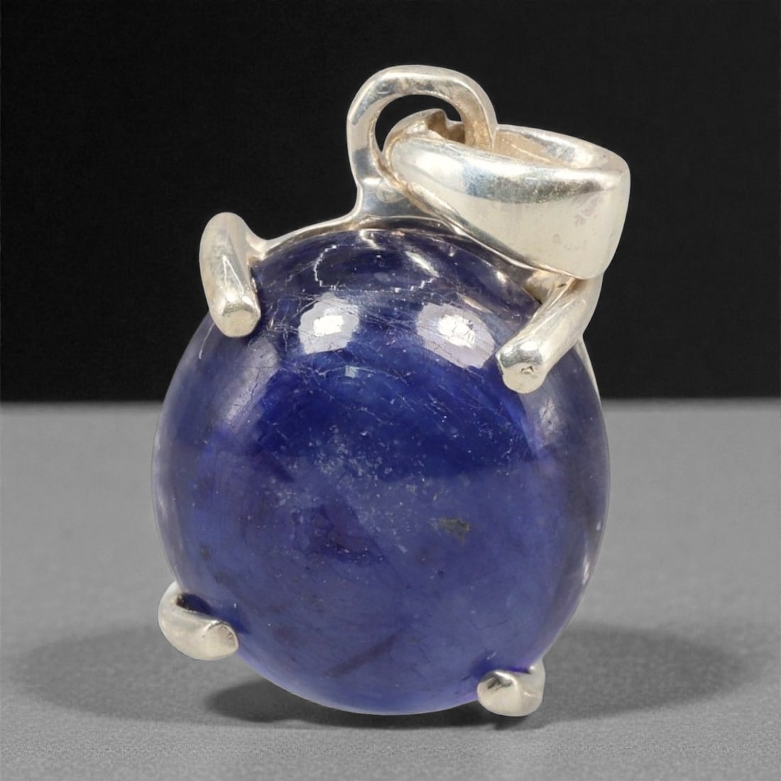 10.67 Carats Deep Blue Sapphire Cabochon Pendant - Sterling Silver Setting, 150A: This striking pendant features a substantial deep blue sapphire cabochon, set in a polished sterling silver frame stamped 925. The cabochon's smooth, domed surface radiates with a rich, velvety blue h