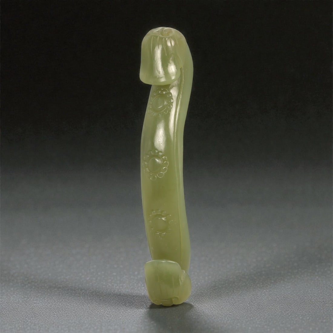 A Chinese Nephrite Jade Belt Hook, 20th Century, 72YA: Carved from pale green nephrite jade with a soft, even translucency, the belt hook is formed as a slender, slightly arched shaft terminating in stylized animal-head finials at both ends. The upper ter