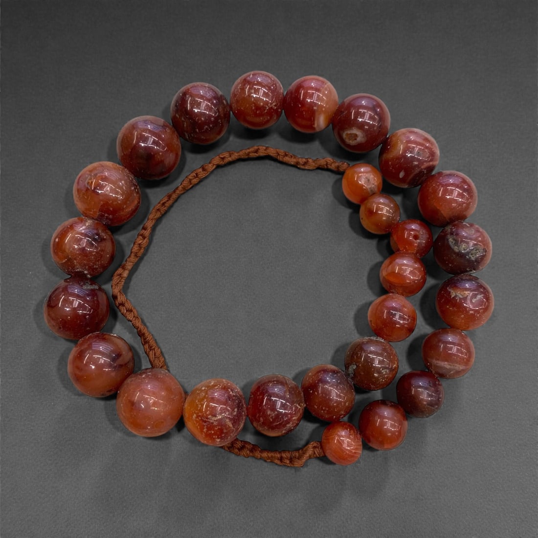 An Antique Indian Carnelian Bead Necklace Strand, 19th Century, 231g, 34AA: Composed of graduated spherical carnelian beads in warm reddish-orange hues, strung on a period braided fiber cord. Carnelian has been a prized gemstone in India for over 2,000 years, valued for its v