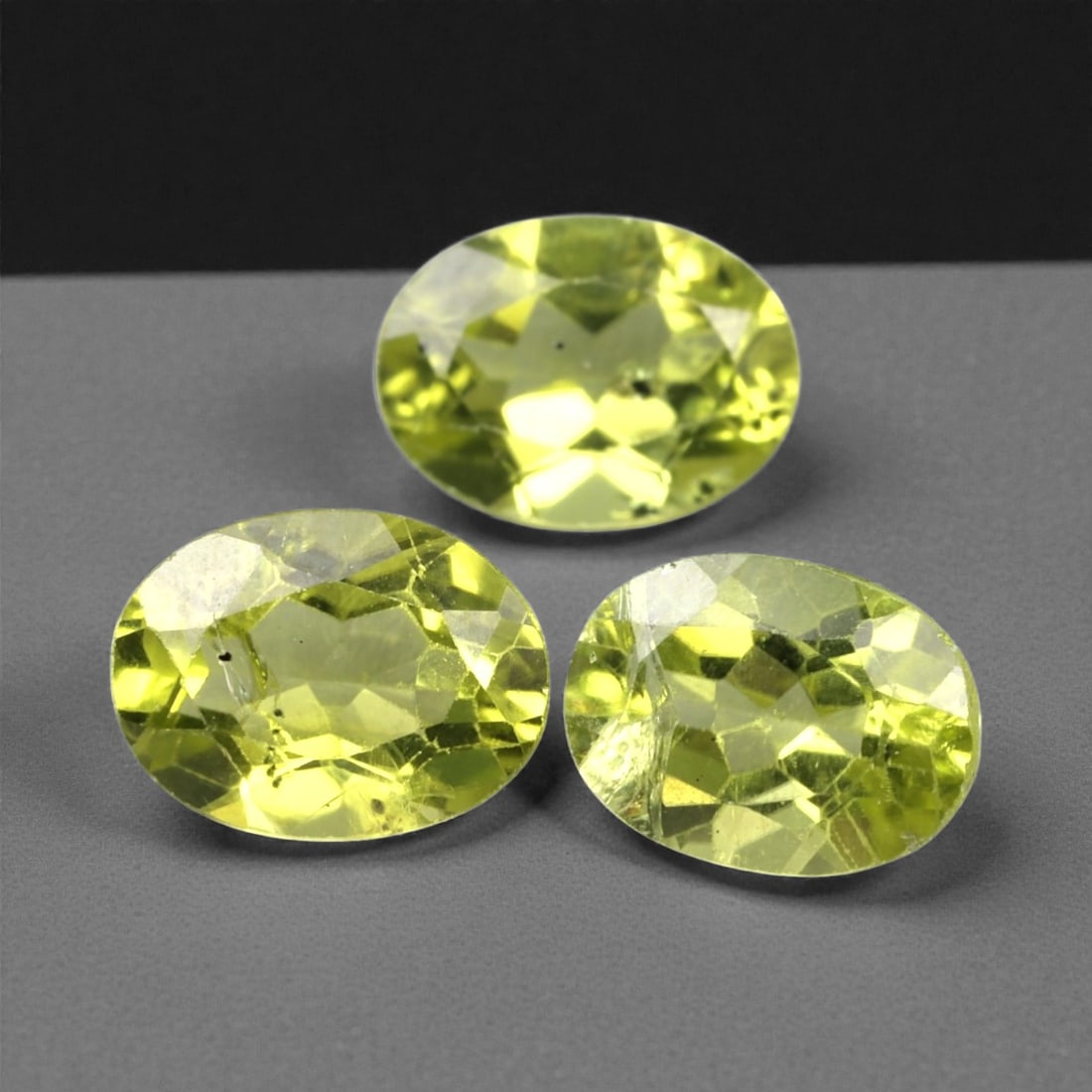 3.89 Carats Bright Green Peridot Selection - Natural Pakistani Stones, 316A: This curated selection of three oval-cut peridot gems radiates with a vibrant, lime-green hue, evoking the lush vibrancy of sunlit tropical foliage. Each stone is precision-faceted to maximize light d