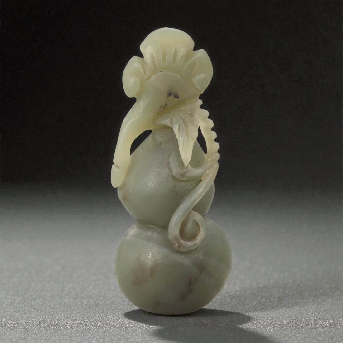 A Chinese Nephrite Jade Double-Gourd Carving, 20th Century, 18FB: Carved from pale celadon nephrite jade with soft translucency and scattered natural inclusions, the object is modeled as a vertical double-gourd (huluhu) form composed of two globular sections joined