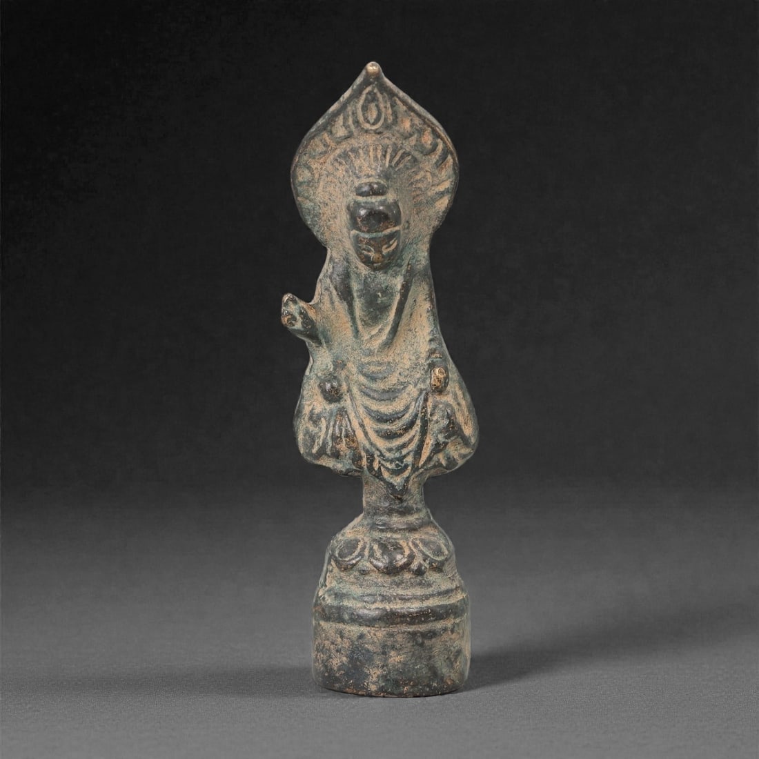 A Chinese Bronze Figure of a Standing Buddhist Deity, Qing Dynasty, 34FG: Cast in bronze with a dark surface and extensive greenish and brown patination, the figure depicts a standing Buddhist deity shown frontally, wearing long flowing robes that fall in rhythmic folds to