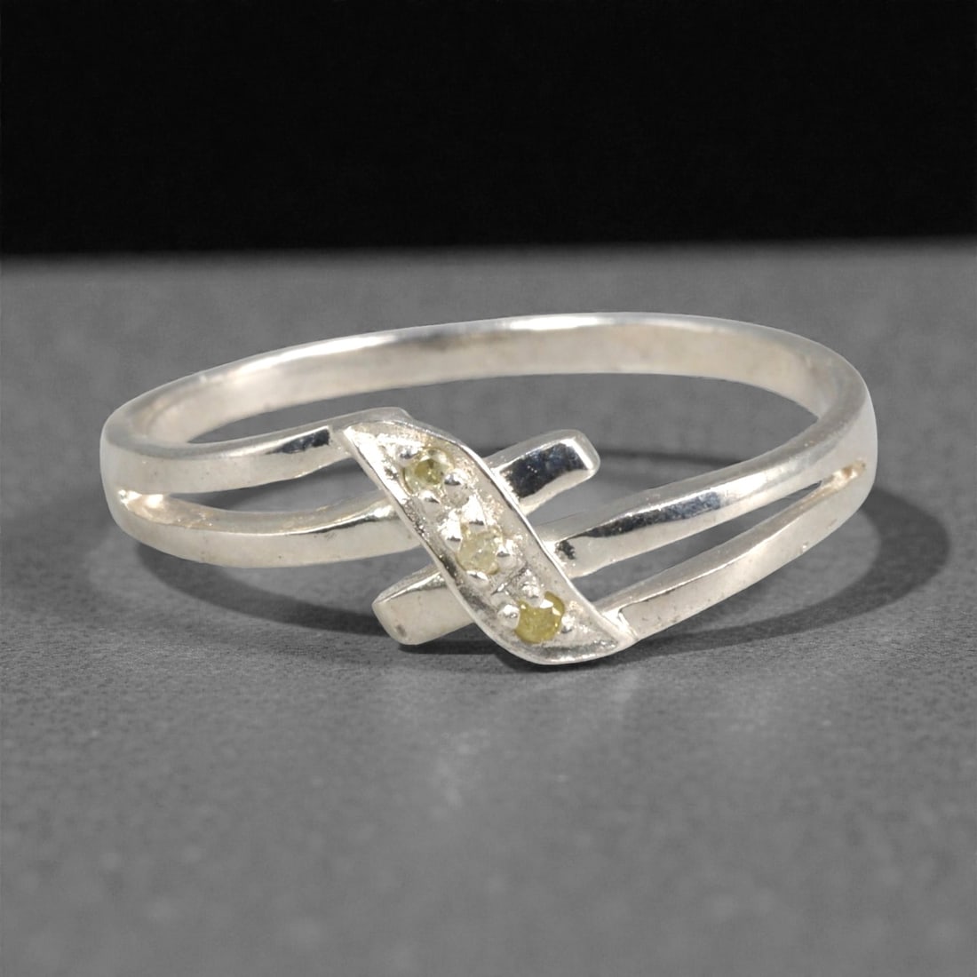 Sterling Silver (925) Ring with Three Yellow Diamonds - Size 6 US, 133A: This modern ring is crafted from polished sterling silver, featuring a distinctive crisscross split-shank design. The centerpiece is a curved, pave-set bar that holds three small, round-cut yellow dia