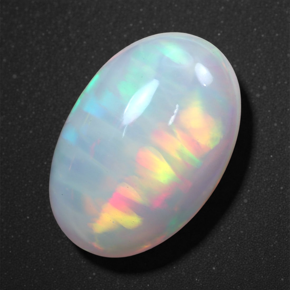 3.37 Carats Rainbow Fire Welo Opal - Natural Ethiopian Gemstone 14.9x9.7x5.1mm, 2XH: This captivating Welo opal displays a vivid kaleidoscope of spectral color, shimmering through a milky translucent body with remarkable intensity. Electric greens, warm ambers, and fiery reds ripple a