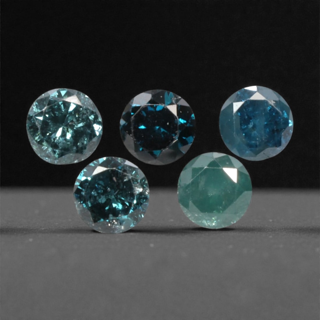 5 Pieces Irradiated Blue Diamond Parcel - Round Brilliant Cut, 2.4mm, 259A: This striking parcel of five loose irradiated blue diamond gems captivates with a vivid, cool blue hue that evokes the intensity of a deep ocean and the clarity of a winter sky. Each stone is cut in a
