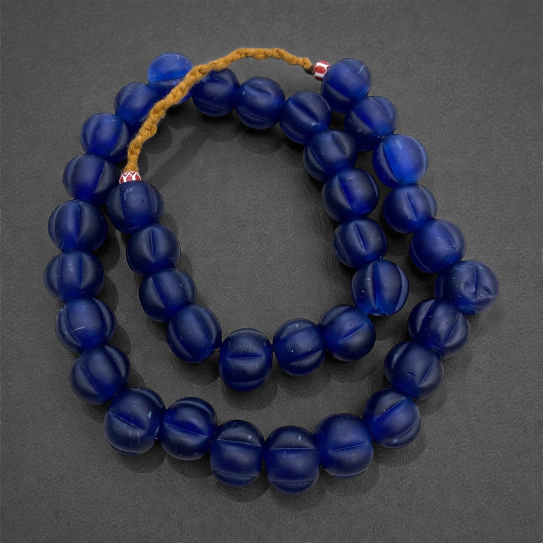 A Chinese Glass Melon Bead Necklace Strand, 19th-Early 20th Century, 3AA: Composed of translucent cobalt blue glass beads formed into a melon shape with molded vertical facets, strung on a modern braided fiber cord. The beads have a matte, frosted surface with subtle variat