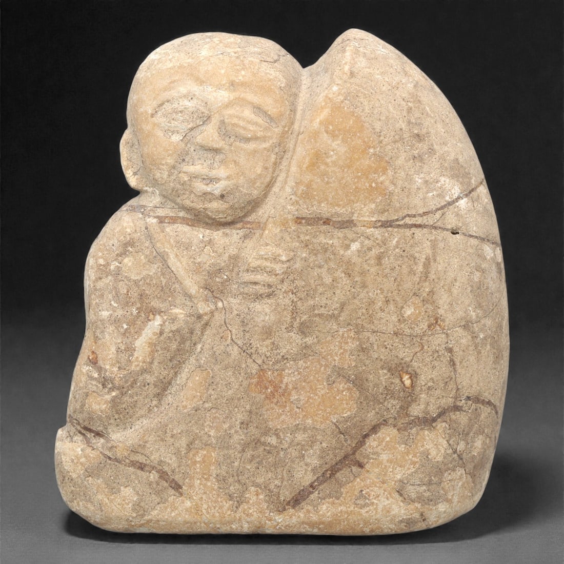 A Japanese Stone Monk Figure, Edo Period, 22ZH: Carved from light beige stone with natural brownish patination and visible fissures, the figure depicts a seated monk in a compact, rounded form. The head is rendered with closed eyes, a broad nose, a