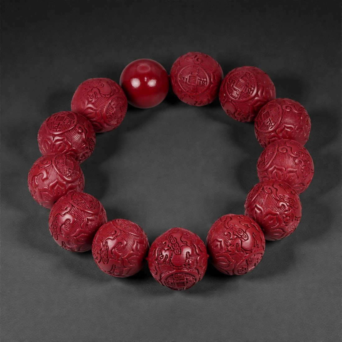 A Chinese Cinnabar Bead Bracelet, 20th Century, 98FD: Composed of spherical beads carved from cinnabar, a mercury sulfide mineral traditionally used in Chinese decorative and ritual objects. The beads are uniformly shaped and pierced centrally, strung to