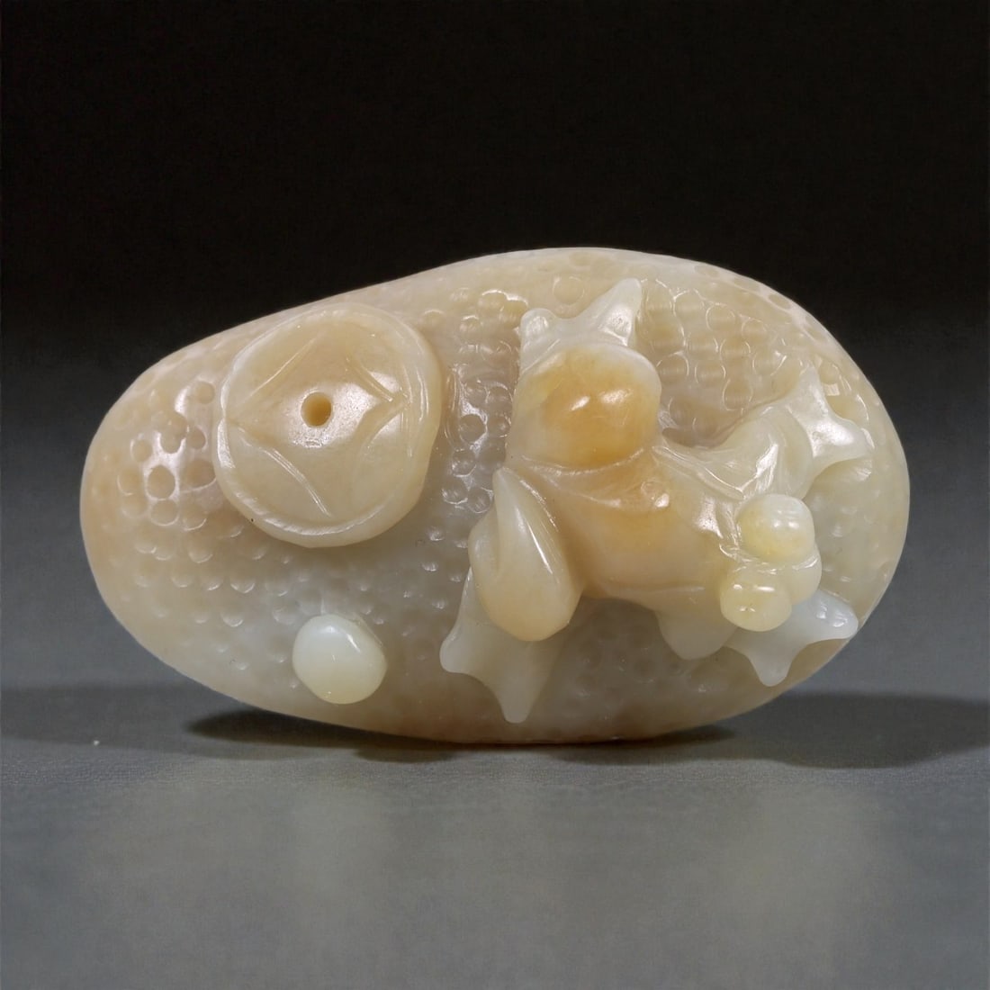 A Chinese Nephrite Jade Frog and Coin Ornament, 20th Century, 97FA: Carved from pale cream nephrite jade with areas of honey-colored translucency, the object is worked as a compact sculptural group depicting a frog shown in relief beside a round coin motif. The frog i